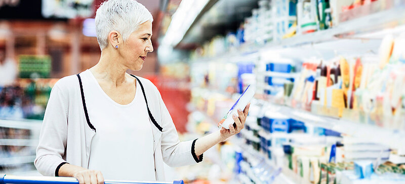 Žena stojí v supermarketu před oddělením s chlazeným zbožím