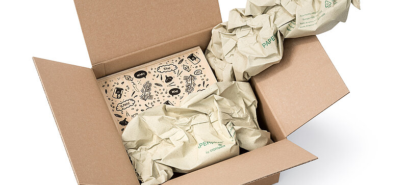 Kartonová krabice s dřevěným boxem a pásy papírových polštářů vyrobených z papíru z trávy