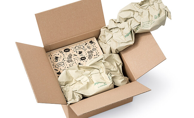 Kartonová krabice s dřevěným boxem a pásy papírových polštářů vyrobených z papíru z trávy