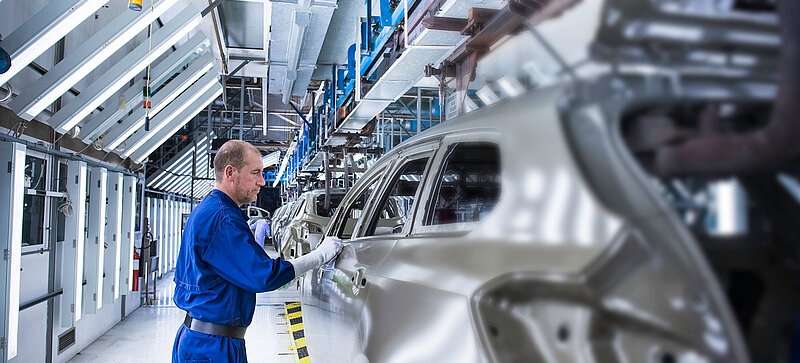 Muž pracuje na automobilu ve výrobním závodě