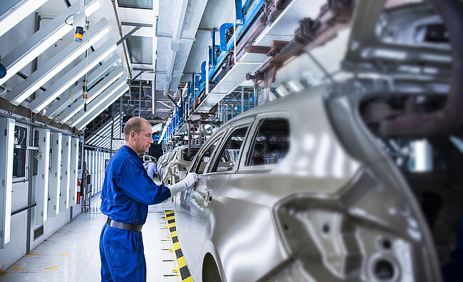 Muž pracuje na automobilu ve výrobním závodě